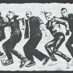 Grafika na ceglanej ścianie przedstawia pięciu mężczyzn w ruchu, przypominających taniec lub bieg. Logo "COMA" widnieje w lewym górnym rogu.