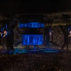 Koncert Dawida Podsiadło, tłum z zapalonymi światłami, wielkie ekrany z wizerunkiem artysty.