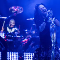 Jonathan Davis z Korn śpiewa z pasją, a w tle widać perkusistę. To scena z koncertu, jak z okładek korn albumy.