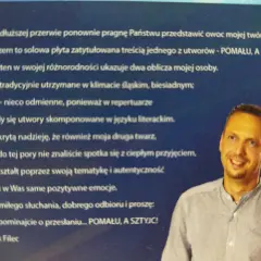 Portret Leszka Fileca, uśmiechniętego mężczyzny w koszuli, na tle tekstu.
