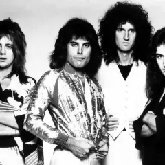 Czterech członków zespołu Queen, w tym Freddie Mercury, w stylizacjach z lat 70. Ich piosenki to ponadczasowe hity.