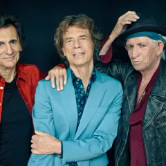 Trzech legendarnych muzyków Stonesów: Ronnie Wood w czerwonej kurtce, Mick Jagger w błękitnym garniturze i Keith Richards w skórzanej ramonesce.