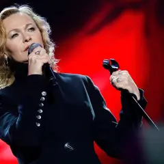 Edyta Geppert śpiewa, trzymając mikrofon. Jej charakterystyczne utwory poruszają serca słuchaczy.