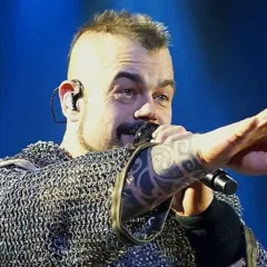 Wokalista Sabaton w kolczudze, z tatuażem na ręce, śpiewa na koncercie. Jego albumy to historie wojenne.