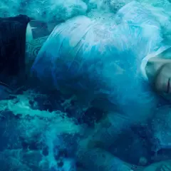 Ed Sheeran zanurzony w wodzie, jak na okładkach jego albumów. Woda tworzy surrealistyczną, błękitną mgłę wokół artysty.