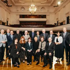 Uczestnicy międzynarodowego konkursu pianistycznego im. Fryderyka Chopina pozują do wspólnego zdjęcia w eleganckiej sali koncertowej.