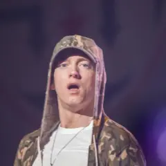 Eminem jak teraz wygląda, w bluzie z kapturem w kamuflażu i białej koszulce, z otwartymi ustami.