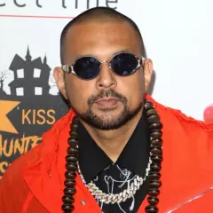 Sean Paul w pomarańczowej kurtce i okularach, gotowy do wykonania swoich hitowych sean paul utwory.