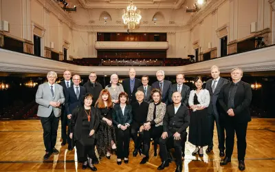 Uczestnicy międzynarodowego konkursu pianistycznego im. Fryderyka Chopina pozują do wspólnego zdjęcia w eleganckiej sali koncertowej.