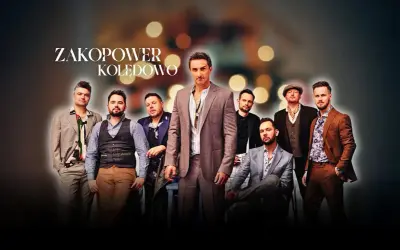Grupa Zakopower w eleganckich strojach, z wokalistą na pierwszym planie, gotowa do kolędowania.