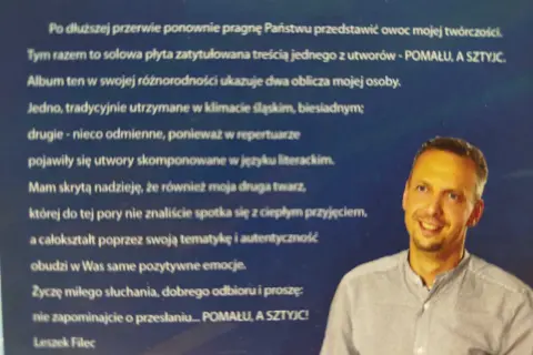 Portret Leszka Fileca, uśmiechniętego mężczyzny w koszuli, na tle tekstu.