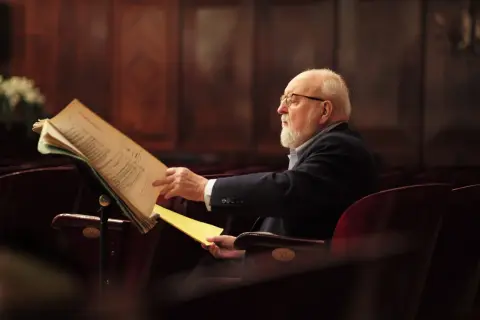 Krzysztof Penderecki w okularach, pochylony nad nutami. Ciekawe, co komponuje?