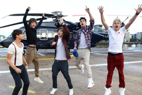 Chłopcy z One Direction skaczą z radości obok helikoptera, jakby właśnie usłyszeli swoje nowe piosenki.