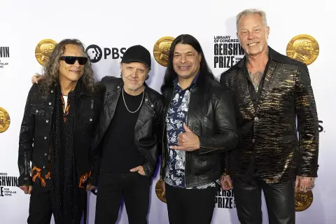 Członkowie zespołu Metallica pozują do zdjęcia. Kirk Hammett, Lars Ulrich, Robert Trujillo i James Hetfield wyglądają elegancko.