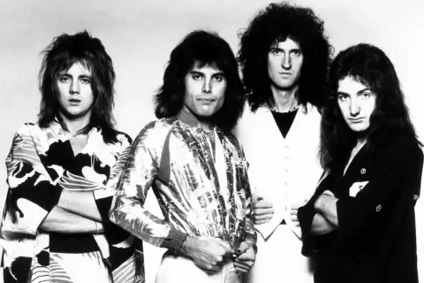 Czterech członków zespołu Queen, w tym Freddie Mercury, w stylizacjach z lat 70. Ich piosenki to ponadczasowe hity.