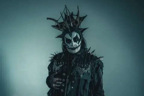 Postać w makijażu przypominającym czaszkę, z kolcami i łańcuchami, idealna do **death metal**owej sesji.