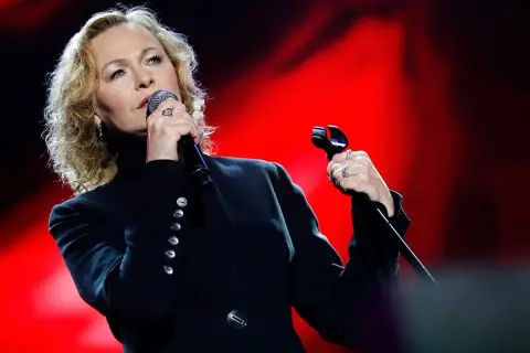 Edyta Geppert śpiewa, trzymając mikrofon. Jej charakterystyczne utwory poruszają serca słuchaczy.