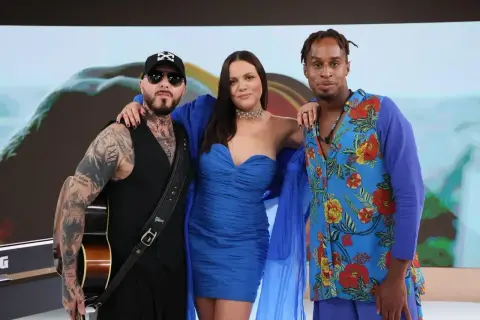 Trzech członków Blue Café w niebieskich strojach. Jeden z nich trzyma gitarę.