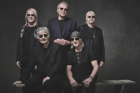 Pięciu członków Deep Purple w czarnych strojach i okularach przeciwsłonecznych pozuje do zdjęcia.