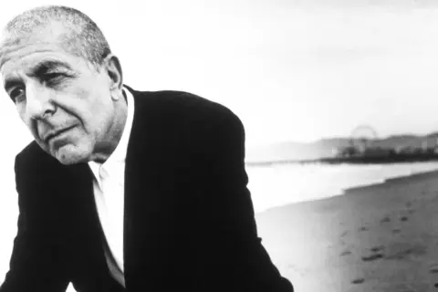 Leonard Cohen, w czerni i bieli, na plaży. Jego głębokie, poruszające utwory odzwierciedlają jego duszę.