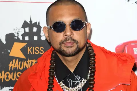 Sean Paul w pomarańczowej kurtce i okularach, gotowy do wykonania swoich hitowych sean paul utwory.
