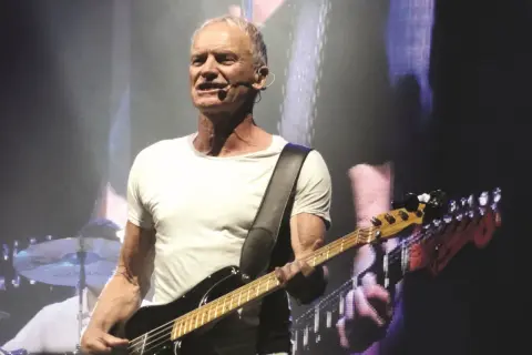 Sting gra na gitarze basowej, wykonując swoje niezapomniane utwory.