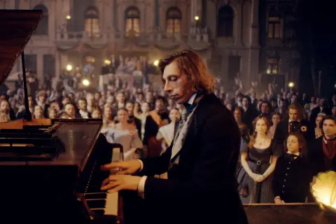 Młody pianista, jakby uczeń Chopina, gra na fortepianie przed zgromadzoną publicznością w historycznym stroju.