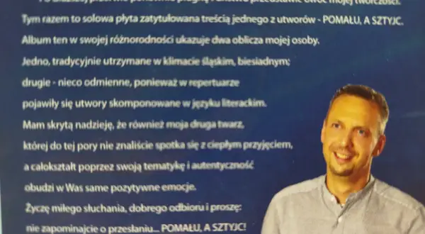 Portret Leszka Fileca, uśmiechniętego mężczyzny w koszuli, na tle tekstu.