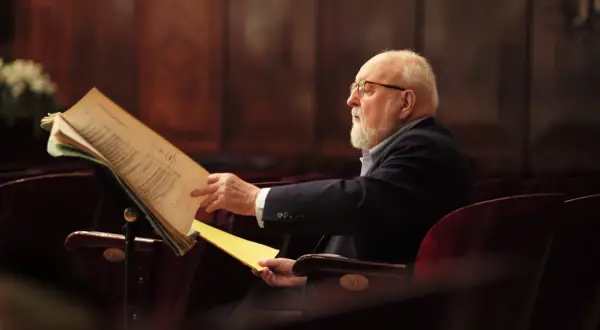 Krzysztof Penderecki w okularach, pochylony nad nutami. Ciekawe, co komponuje?