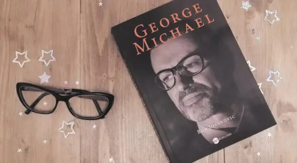 Okładka książki o George'u Michaelu, obok okulary i gwiazdki. Idealna lektura dla fanów jego albumów.