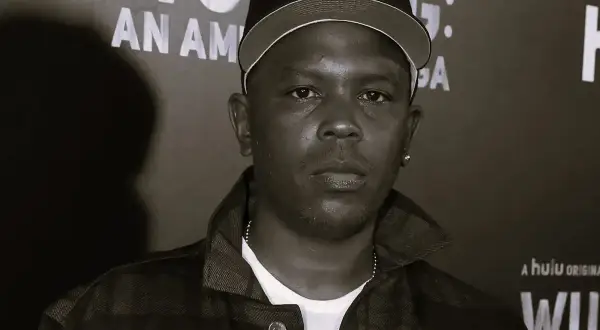 Członek Wu-Tang Clan w czapce z daszkiem i kratkowanej kurtce, na tle napisu "Wu-Tang: An American Saga".