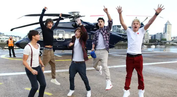 Chłopcy z One Direction skaczą z radości obok helikoptera, jakby właśnie usłyszeli swoje nowe piosenki.