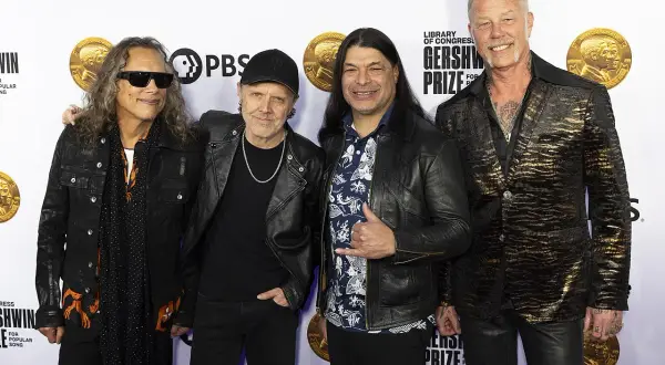 Członkowie zespołu Metallica pozują do zdjęcia. Kirk Hammett, Lars Ulrich, Robert Trujillo i James Hetfield wyglądają elegancko.