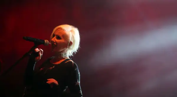 Kora Jackowska śpiewa na scenie, wykonując swoje utwory. Wokół niej unosi się mgła, a czerwone światła tworzą nastrojową atmosferę.