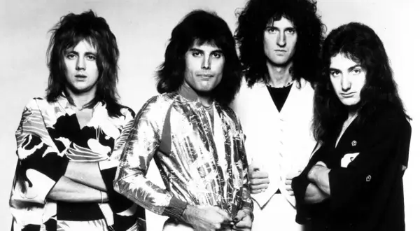 Czterech członków zespołu Queen, w tym Freddie Mercury, w stylizacjach z lat 70. Ich piosenki to ponadczasowe hity.