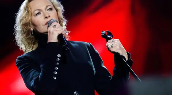 Edyta Geppert śpiewa, trzymając mikrofon. Jej charakterystyczne utwory poruszają serca słuchaczy.