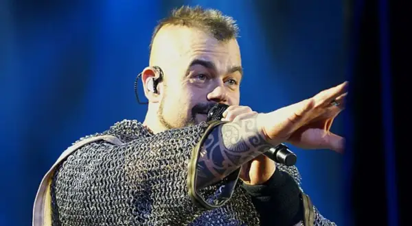 Wokalista Sabaton w kolczudze, z tatuażem na ręce, śpiewa na koncercie. Jego albumy to historie wojenne.