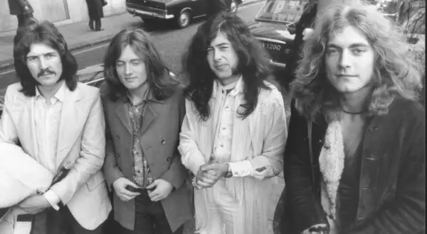 Czterech członków Led Zeppelin pozuje do zdjęcia na ulicy. John Bonham, John Paul Jones, Jimmy Page i Robert Plant wyglądają stylowo.