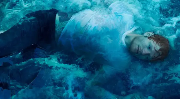Ed Sheeran zanurzony w wodzie, jak na okładkach jego albumów. Woda tworzy surrealistyczną, błękitną mgłę wokół artysty.