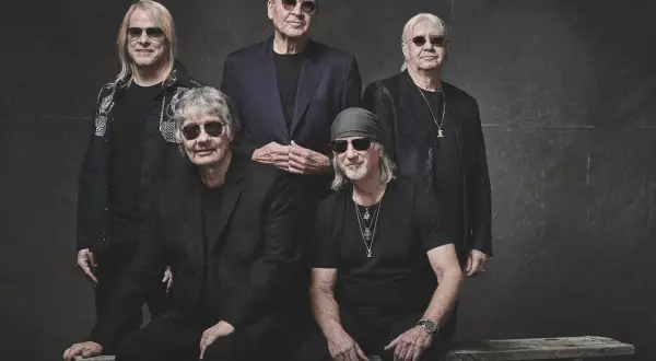 Pięciu członków Deep Purple w czarnych strojach i okularach przeciwsłonecznych pozuje do zdjęcia.