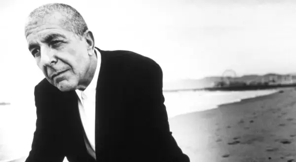 Leonard Cohen, w czerni i bieli, na plaży. Jego głębokie, poruszające utwory odzwierciedlają jego duszę.