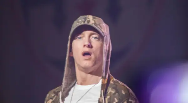 Eminem jak teraz wygląda, w bluzie z kapturem w kamuflażu i białej koszulce, z otwartymi ustami.