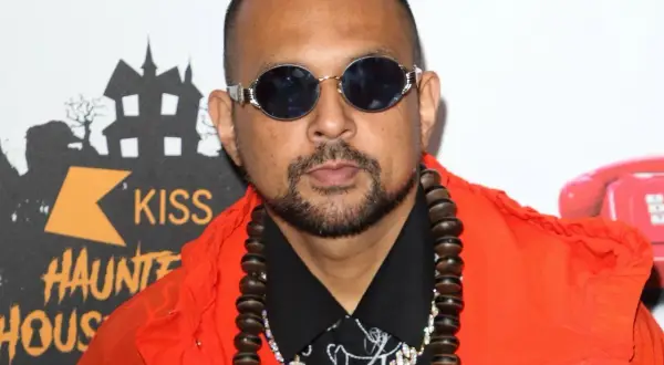 Sean Paul w pomarańczowej kurtce i okularach, gotowy do wykonania swoich hitowych sean paul utwory.