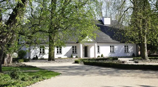 Biały dworek otoczony zielenią, idealne miejsce na letnie koncerty w Żelazowej Woli.