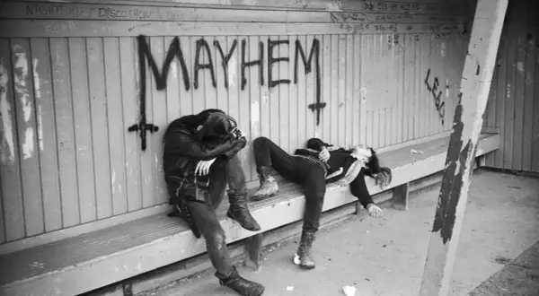 Dwie postacie w mrocznym stylu, leżące na ławce pod napisem "MAYHEM". Może to być okładka jednego z albumów zespołu Mayhem.