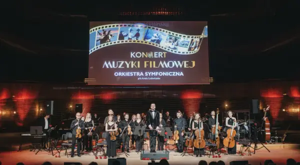 Koncert muzyki filmowej w Katowicach. Orkiestra symfoniczna na scenie pod ekranem z tytułem wydarzenia.