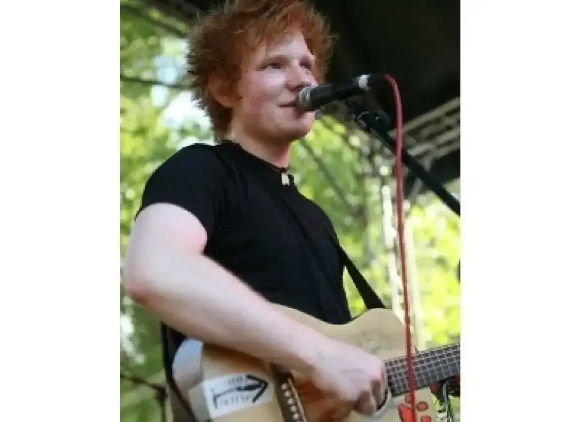 Ed Sheeran gra na gitarze, śpiewając do mikrofonu. Czy Ed Sheeran ma dzieci? Tak, jest ojcem dwójki.