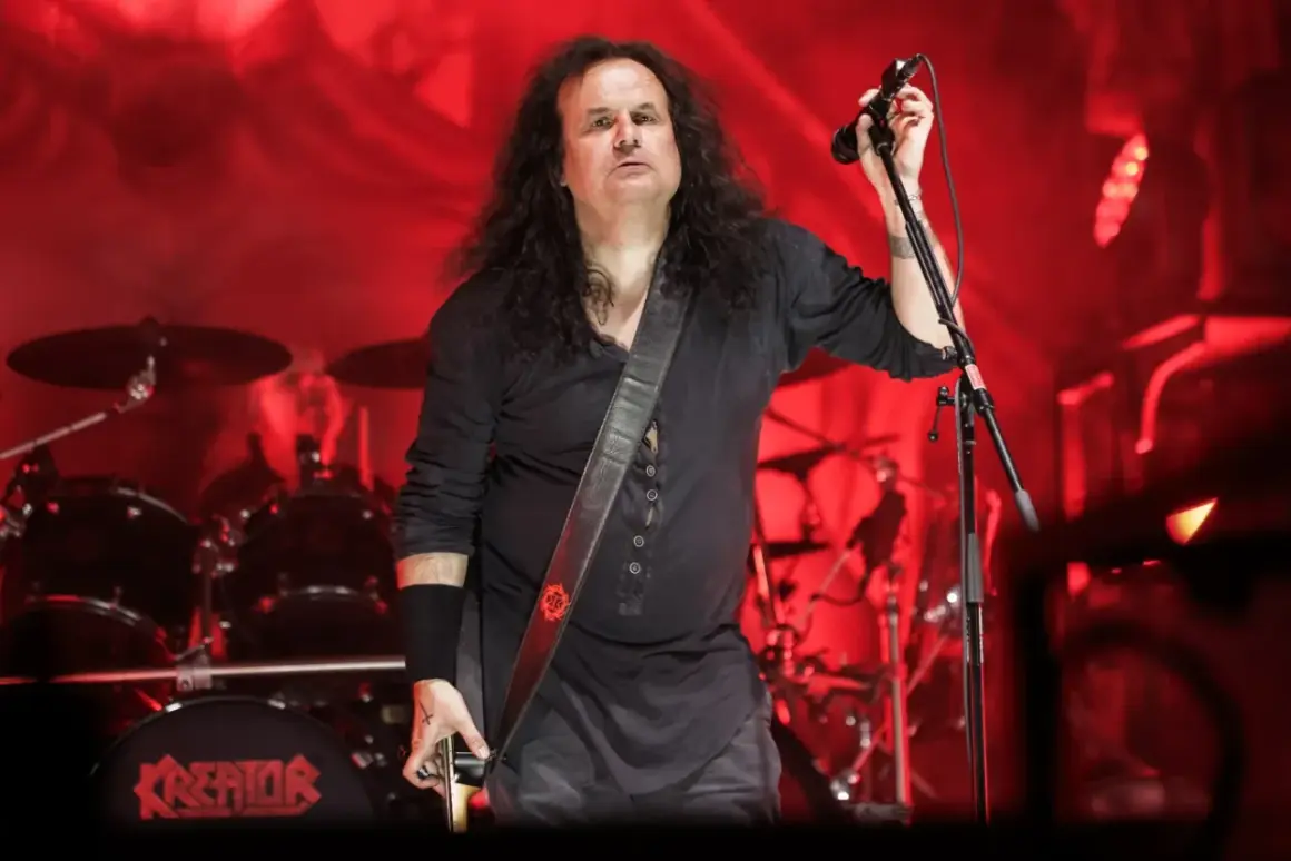 Miland "Mille" Petrozza, lider zespołu Kreator, podczas koncertu. Na bębnie widnieje logo Kreator, co podkreśla jego rolę jako kreatora albumów.