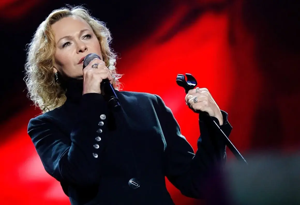 Edyta Geppert śpiewa, trzymając mikrofon. Jej charakterystyczne utwory poruszają serca słuchaczy.