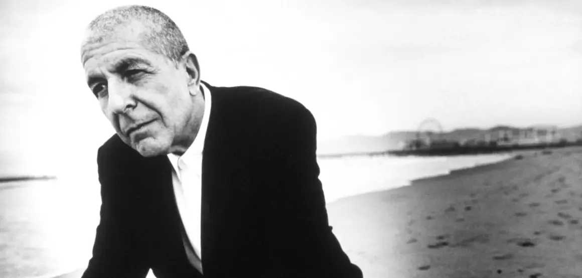 Leonard Cohen, w czerni i bieli, na plaży. Jego głębokie, poruszające utwory odzwierciedlają jego duszę.